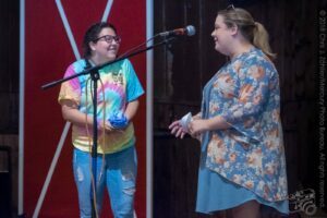 Riley Accepts a T-Shirt As Part of Her Prize Package — Kids’ Songwriting Contest Awards Announcement, 21st Annual Woody Guthrie Festival, 2018